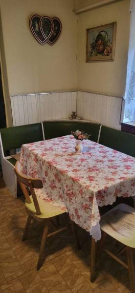 Na predaj starší rodinný dom v obci Ohrady - Jedáleň rodinného domu s rohovou lavicou, kvetinovým obrusom a dekoráciou na stene.