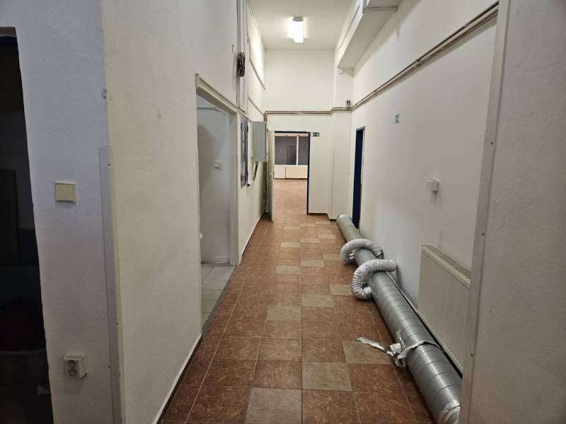 Exkluzívny obchodný priestor na predaj v centre Dunajskej Stredy – ul. - Chodba v obchodných priestoroch s dlažbou, odvetrávací systém a biele steny.