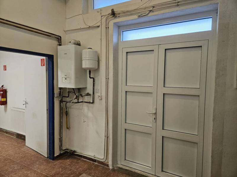 Exkluzívny obchodný priestor na prenájom v centre Dunajskej Stredy – u - Interiérové obchodné priestory s bielymi dverami, kotlom a podlahou s dreveným dekorom.