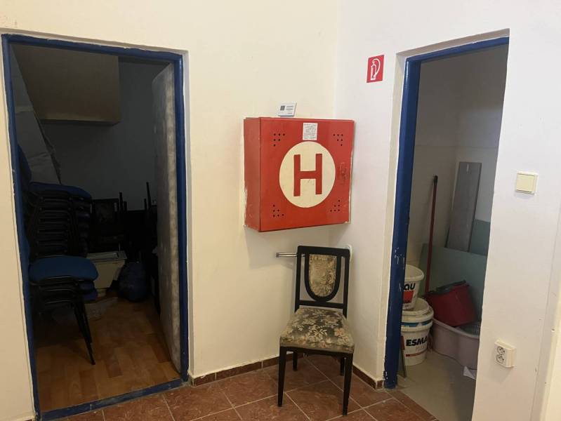 Exkluzívny obchodný priestor na prenájom v centre Dunajskej Stredy – u - Interiér obchodných priestorov s protipožiarnou skrinkou, stoličkou a miestnosťami na uskladnenie.