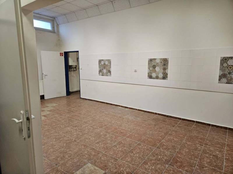 Exkluzívny obchodný priestor na prenájom v centre Dunajskej Stredy – u - Interiér obchodných priestorov s dlažbou a bielymi stenami, zdobenými kachličkami.