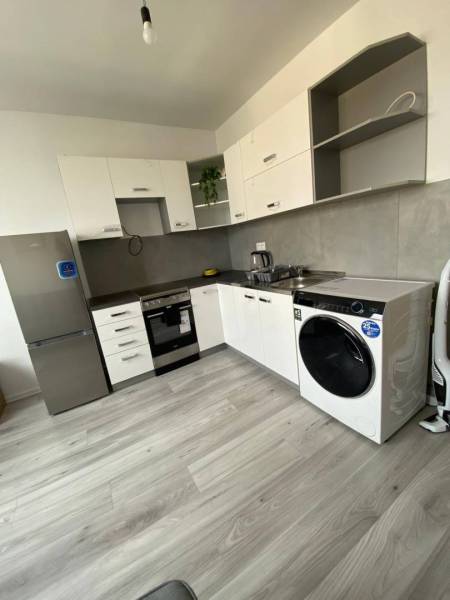 Na prenájom štýlový a moderný 2 izbový byt v centre Dunajskej Stredy - Kuchyňa s bielymi skriňami, spotrebičmi a podlahou s dreveným dekorom v 2-izbovom byte.