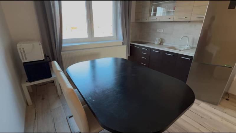 Prenájom 2-izbového bytu, Dunajská Streda - Kuchynský kút v 2-izbovom byte s jedálenským stolom a podlahou s dreveným dekorom.