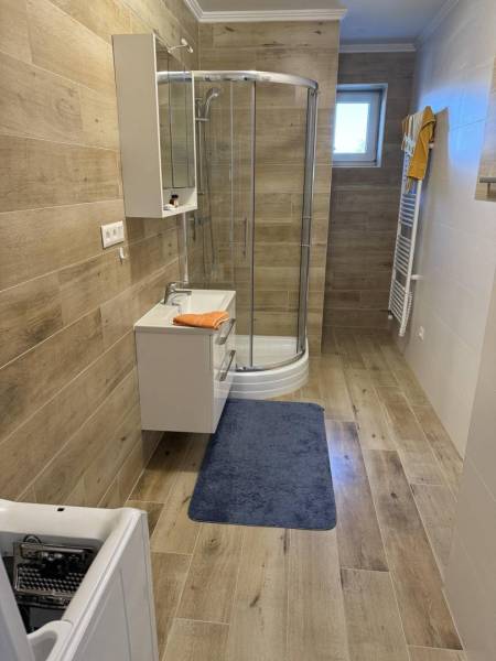Prenájom 2-izbového bytu, Dunajská Streda - Kúpeľňa v 2-izbovom byte s podlahou s dreveným dekorom a sprchovacím kútom.