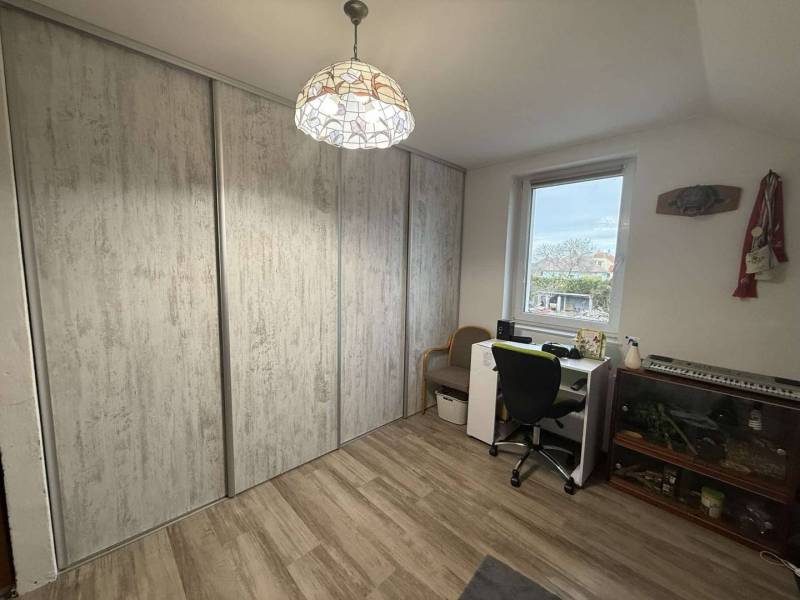 Predaj rodinného domu, Dunajská Streda - Izba v rodinnom dome s pracovným stolom, podlahou s dreveným dekorom a vstavanými skriňami.