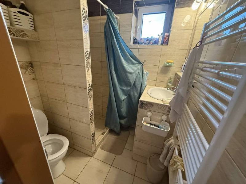Predaj rodinného domu, Dunajská Streda - Kúpeľňa v rodinnom dome s toaletou, sprchou a umývadlom, obložená svetlými dlaždicami.
