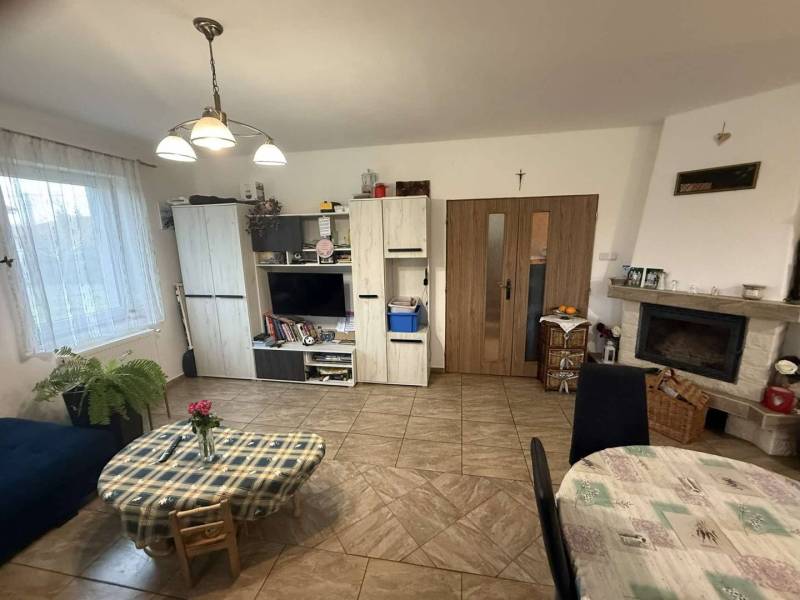 Predaj rodinného domu, Dunajská Streda - Obývacia izba v rodinnom dome s televízorom, krbom a jedálenským stolom.