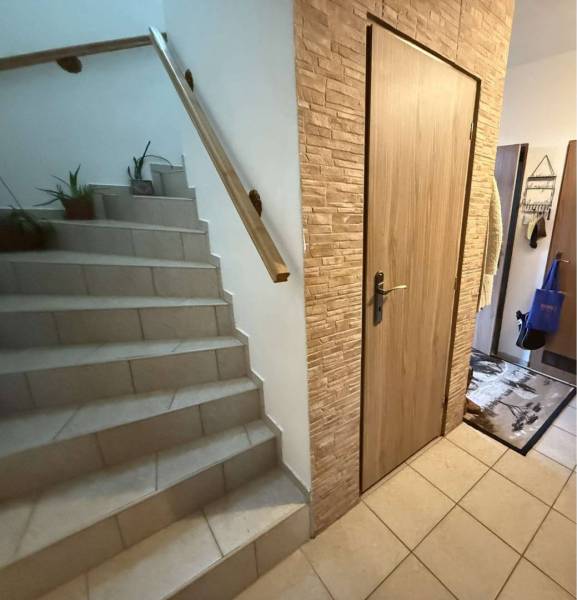 Predaj rodinného domu, Dunajská Streda - Schodisko s kvetmi a dverami v rodinnom dome, podlaha s dreveným dekorom.