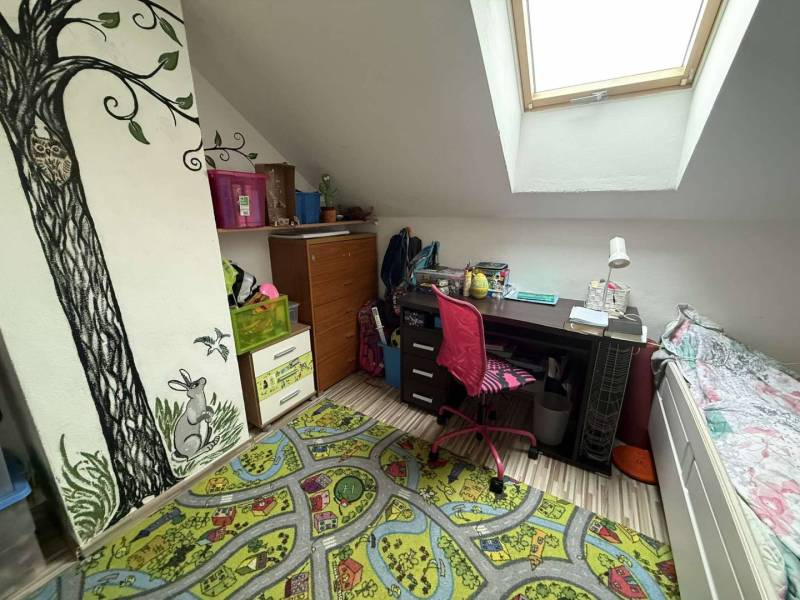 Predaj rodinného domu, Dunajská Streda - Detská izba v podkroví s písacím stolom a farebným kobercom v Rodinnom dome.