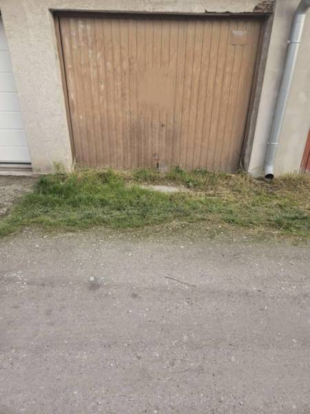 Predaj garáže, Nevädzová, Nevädzová, Dunajská Streda - Hnedé garážové dvere v Dunajskej Strede s betónovým podkladom a zelenou trávou.