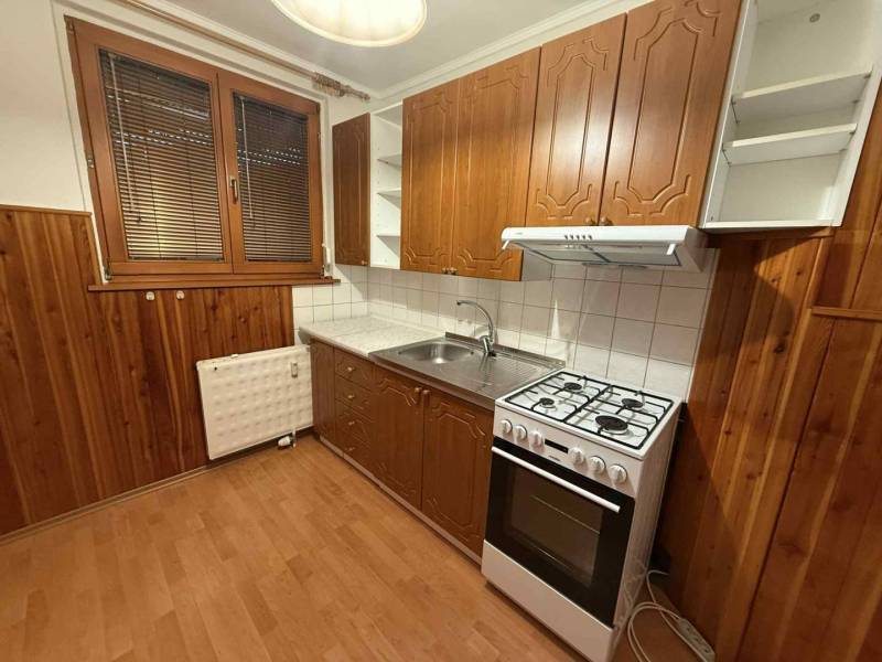 Prenájom 3-izbového bytu, Dunajská Streda - Kuchyňa v 3-izbovom byte s plynovým sporákom, drevenými skrinkami a podlahou s dreveným dekorom.