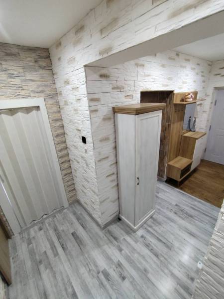 ☎️ 0918197701-Predám 3 izbový byt s loggiou po kompletnej rekonštrukci - Chodba v 3-izbovom byte s kamennými stenami a podlahou s dreveným dekorom.