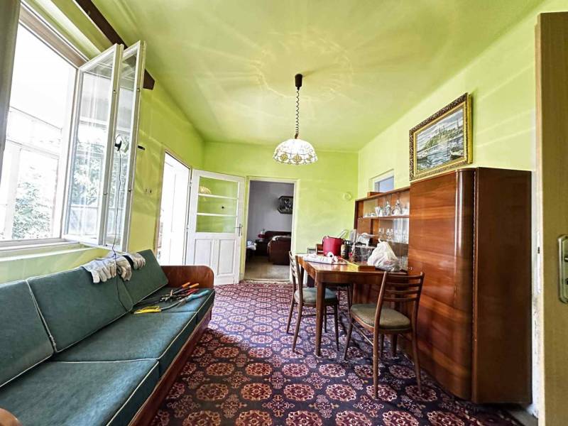 ☎️ 0918197701- Na predaj starší rodinný dom vhodný na kompletnú presta - Obývacia izba rodinného domu s gaučom, jedálenským stolom a sklenenou vitrínou.