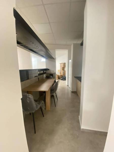 ☎️ 0918197701-Na prenájom väčší obchodný priestor 230 m² v suteréne v  - Interiér obchodných priestorov s dlhým stolom a stoličkami, biele steny, svetlá dlažba.