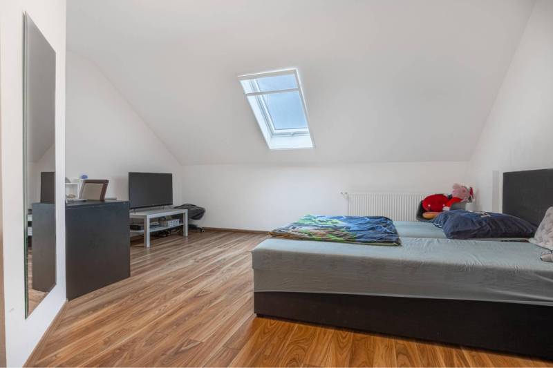 ☎️ 0918197701-Na predaj 5 izbový poschodový rodinný dom s 2 garážou v  - Podkrovná spálňa s posteľou, TV a podlahou s dreveným dekorom v rodinnom dome.