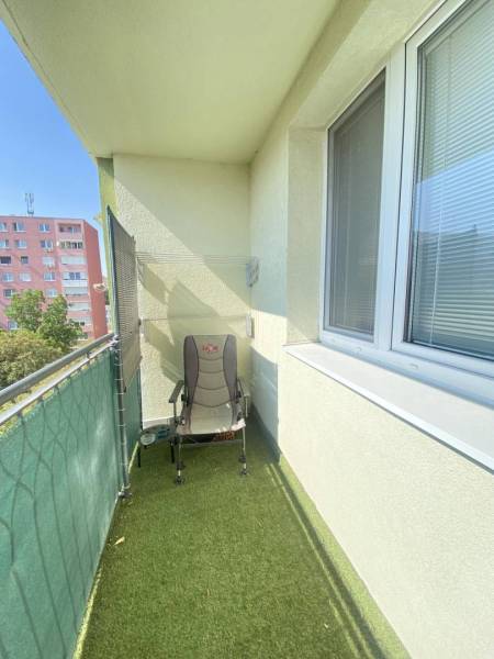 REZERVOVANÉ   0918197701- Výrazná zľava NA PREDAJ  kompletne  zariaden - Balkón 3-izbového bytu v Dunajskej Strede so zeleným kobercom a skladacou stoličkou.