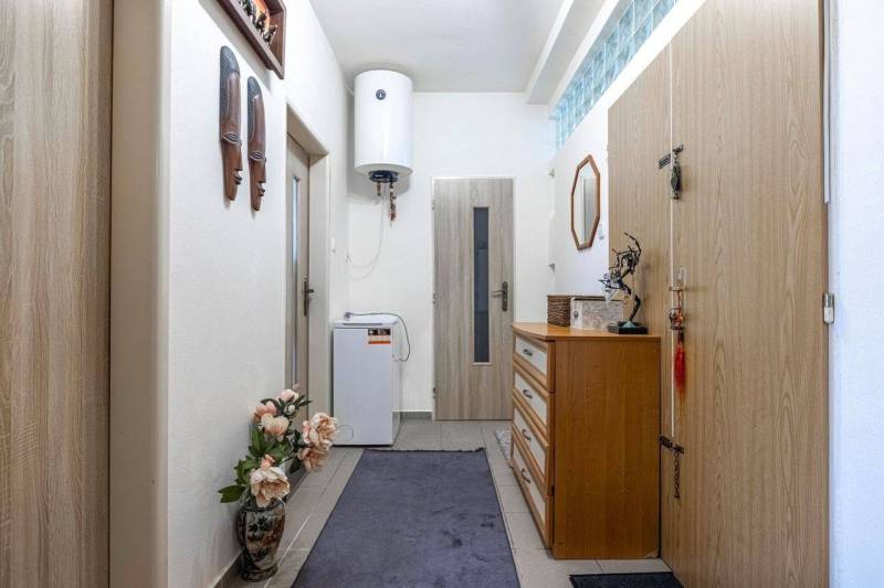 ☎️ 0918197701- PREDAJ - Nebytových priestorov Dunajská Streda - Interiér s drevenými dekoráciami, zrkadlom a komodou, vybavený dekoratívnym kvetom a bojlerom.