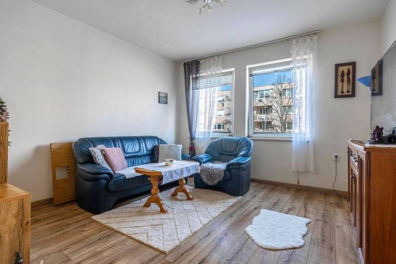 ☎️ 0918197701- PREDAJ - Nebytových priestorov Dunajská Streda - Obývacia izba s modrou sedačkou a podlahou s dreveným dekorom.