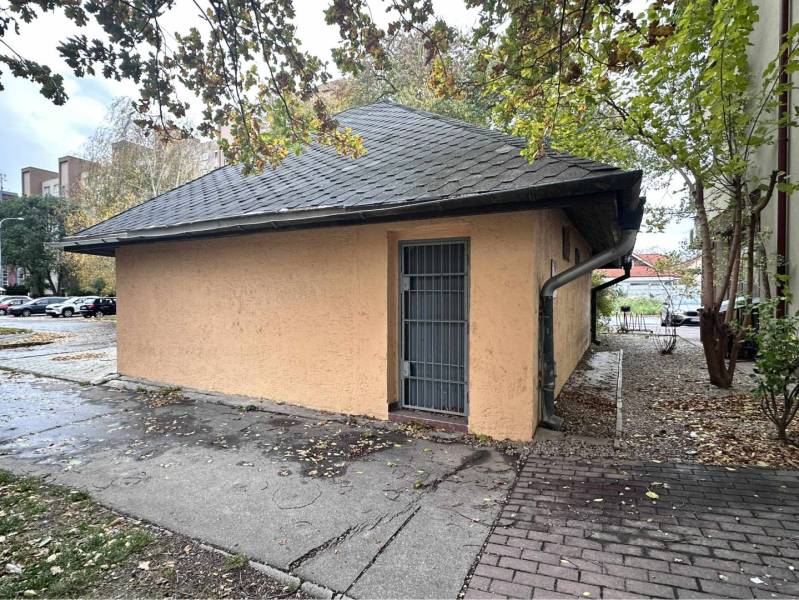 ☎️ 0918197701- Znížená cena     Predaj – Obchodný priestor v Dunajskej - Budova s plechovými dverami obklopená stromami a zaparkovanými autami v Dunajskej Strede.