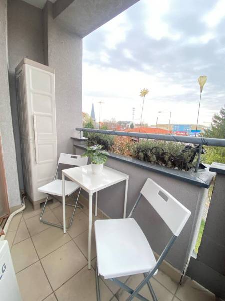 ☎️ 0918197701   Na predaj  elegantný 3 izbový byt priamo v centre Duna - Balkón 3-izbového bytu v Dunajskej Strede s bielym nábytkom a rastlinou.