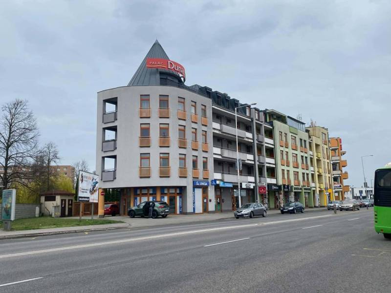 ☎️ 0918197701   Na predaj  elegantný 3 izbový byt priamo v centre Duna - Ulica s budovami, autami a reklamami v Dunajskej Strede.