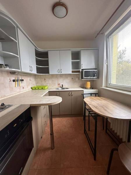 REZERVOVANÉ  ☎️ 0918/197 701 Na prenájom garsónka blízkosti centra mes - Kuchyňa v rekreačnom apartmáne s bielymi skrinkami, barovým pultom a mikrovlnkou.