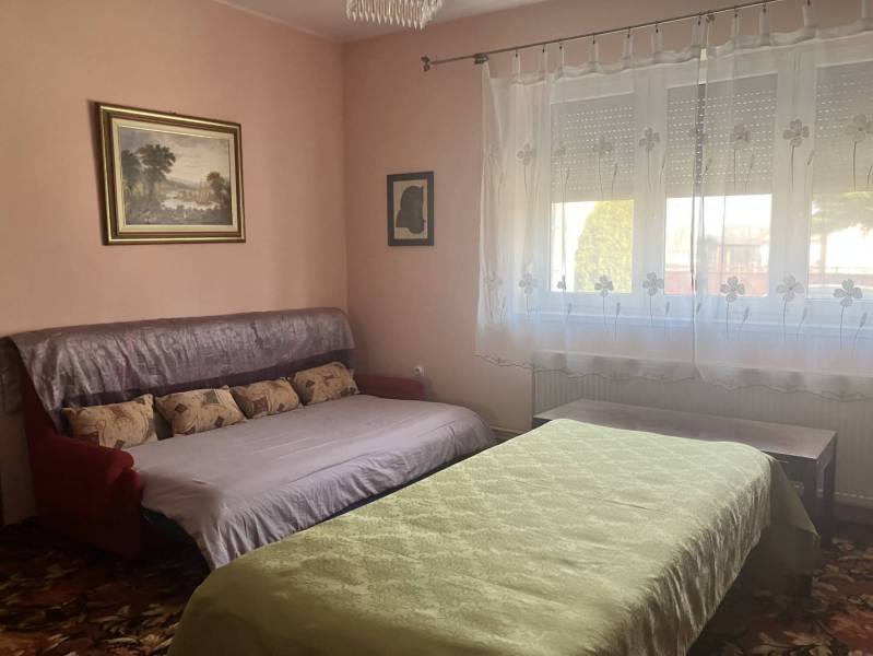 0911 234 656 Predaj rodinný dom v obci Jahodná - Izba v rodinnom dome s gaučom a posteľou, dekoratívnymi vankúšmi a obrazmi na stenách.