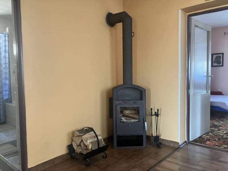 0911 234 656 Predaj rodinný dom v obci Jahodná - Krbová piecka na drevo, podlaha s dreveným dekorom, otvory do ďalších miestností v rodinnom dome.