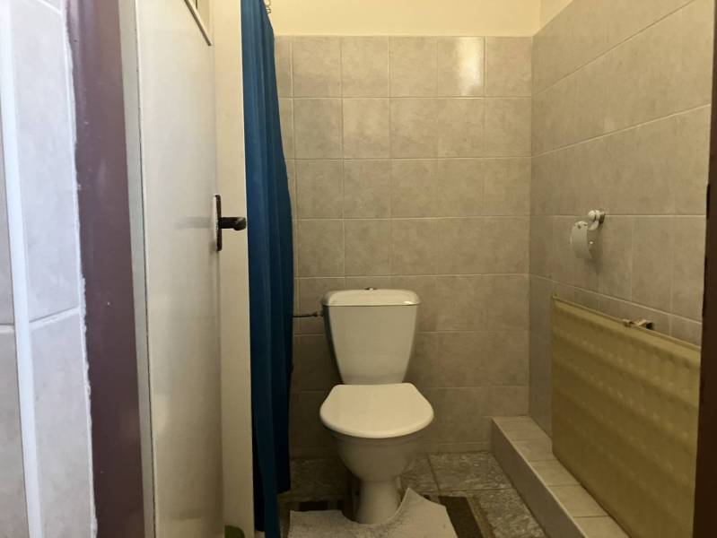 0911 234 656 Predaj rodinný dom v obci Jahodná - Kúpeľňa v rodinnom dome s toaletou, kachličkovými stenami a modrým závesom.