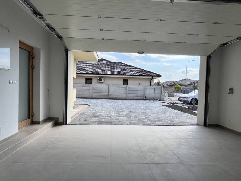 Jedinečný 5 izbový dom na predaj v TOP lokalite-GARDEN TOWN - Rodinný dom s otvorenou garážou, modernou dlažbou a autom v exteriéri.