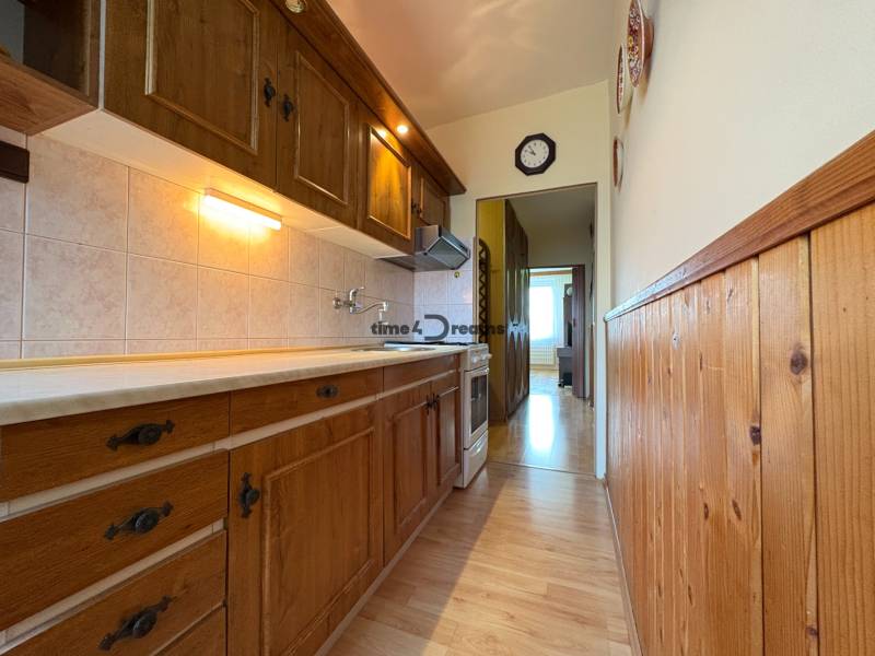 Na predaj: CENTRUM veľký 3 izb.byt + BALKON + ŠATNIK - Kuchyňa s drevenou kuchynskou linkou, obklady a 3-izbový byt vidieť v pozadí.