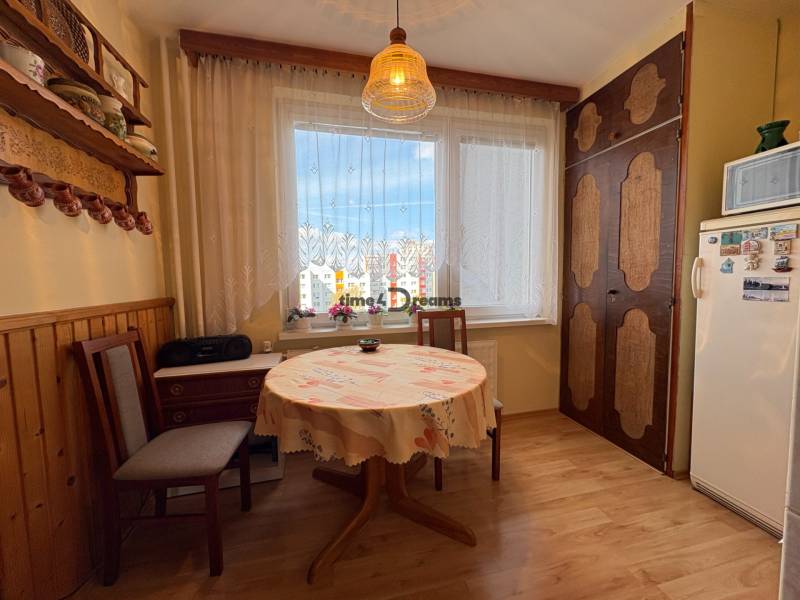 Na predaj: CENTRUM veľký 3 izb.byt + BALKON + ŠATNIK - Útulná kuchyňa s kvetinovými závesmi, rustikálnymi poličkami, stolom a pôsobí súčasťou 3-izbového bytu.