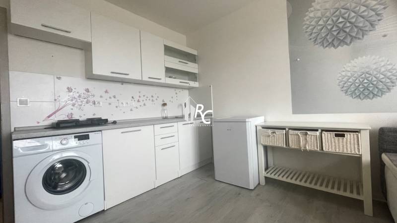 Garsónka na prenájom prerobená a zariadená Vrútky - Kuchynská linka s rúrou, práčkou a minimalistickou dekoráciou v garsónke s podlahou s dreveným dekorom.