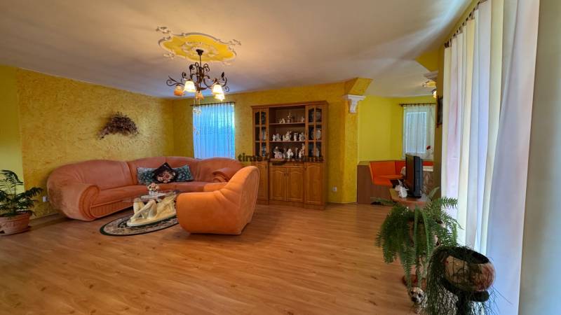 NA PREDAJ 4 izbový rodinný dom Nitrianske Hrnčiarovce - Obývačka v rodinnom dome s pohovkou, skriňou, dekoráciami a podlahou s dreveným dekorom.