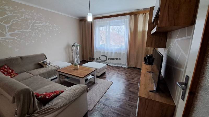 NA PREDAJ 6 izbový rodinný dom v obci Hrušovany  - Obývacia izba v rodinnom dome s podlahou s dreveným dekorom a pohodlnou pohovkou.