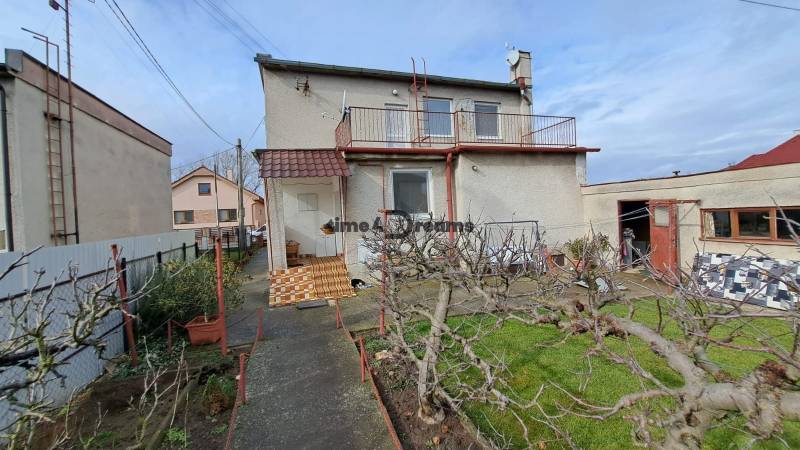 NA PREDAJ 6 izbový rodinný dom v obci Hrušovany  - Rodinný dom v Hrušovanoch so záhradou, upravenými stromami a garážou.