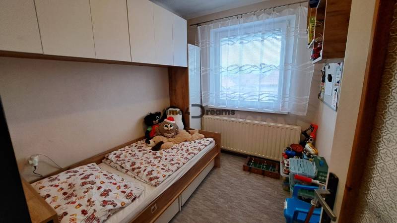 NA PREDAJ 6 izbový rodinný dom v obci Hrušovany  - Detská izba so sivým kobercom, posteľou a hračkami v Rodinnom dome.