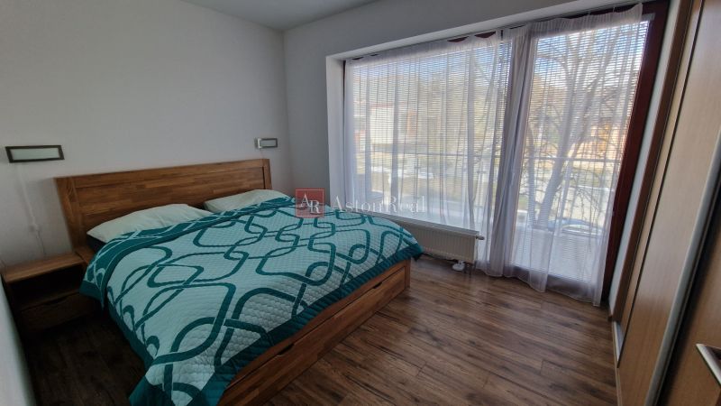 Rekreačný apartmán Vys. Tatry- HREBIENOK RESORT I. - 92 m2 -3-izbový - Spálňa v rekreačnom apartmáne s posteľou, balkónom a podlahou s dreveným dekorom.