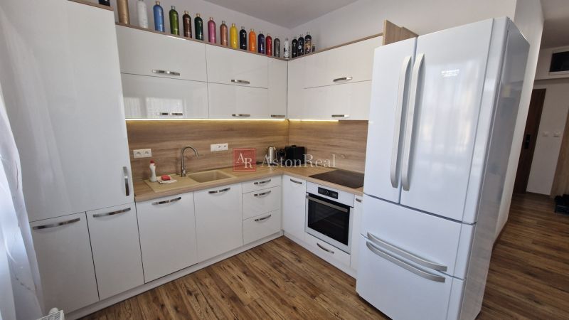 Rekreačný apartmán Vys. Tatry- HREBIENOK RESORT I. - 92 m2 -3-izbový - Kuchyňa v rekreačnom apartmáne s bielymi skrinkami a podlahou s dreveným dekorom.
