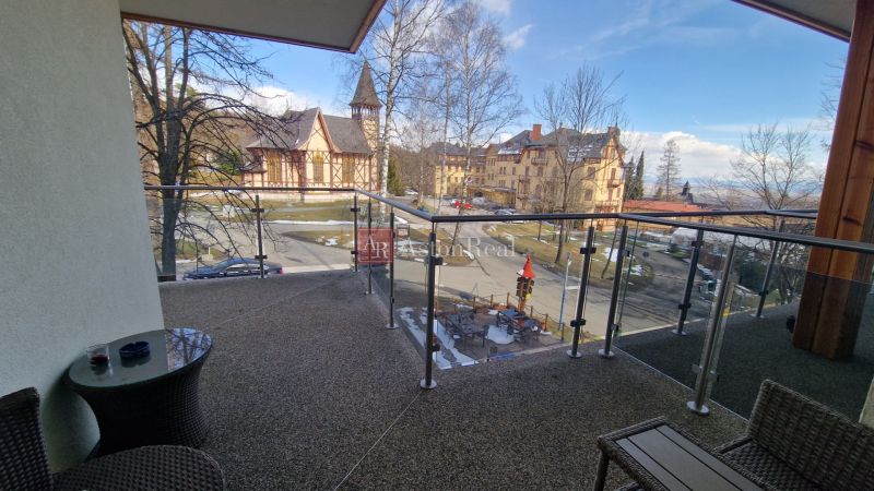 Rekreačný apartmán Vys. Tatry- HREBIENOK RESORT I. - 92 m2 -3-izbový - Balkón rekreačného apartmánu s výhľadom na kostol a architektúru v Starom Smokovci, Vysoké Tatry.