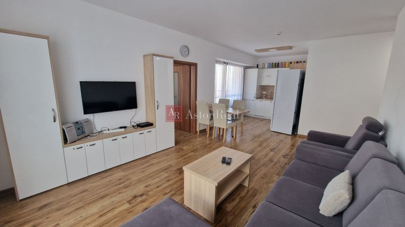 Rekreačný apartmán Vys. Tatry- HREBIENOK RESORT I. - 92 m2 -3-izbový - Obývacia izba rekreačného apartmánu s televízorom, sedačkou, jedálenským stolom a podlahou s dreveným dekorom.