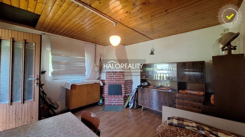 Predaj, chata Revúca - EXKLUZÍVNE HALO REALITY - Interiér útulnej chaty s podlahou s dreveným dekorom a krbom.