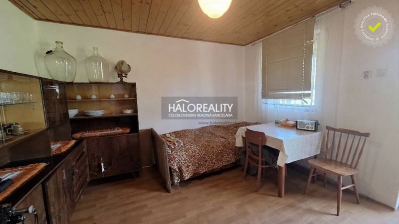 Predaj, chata Revúca - EXKLUZÍVNE HALO REALITY - Izba na chate s podlahou s dreveným dekorom, zariadená nábytkom a jedálenským stolom.