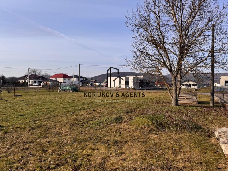 PREDAJ, Veľký stavebný pozemok v Kamenici Nad Cirochou - Pozemok na bývanie v Kamenici nad Cirochou na Ružovej ulici, s výhľadom na domy.
