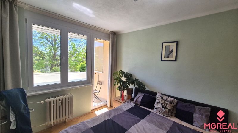 Prenájom 2izbový byt Topoľčany  - Spálňa v 2-izbovom byte so vstupom na balkón a izbovou rastlinou.