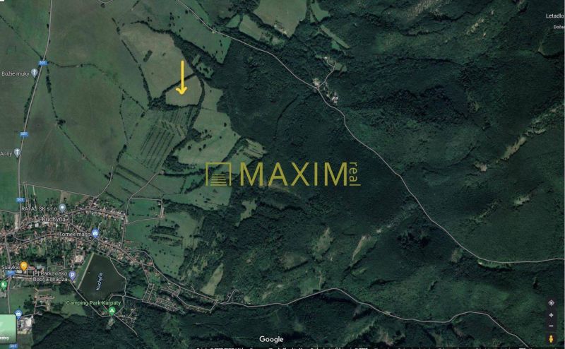 Slnečný takmer hektárový pozemok (9410m²) v k.ú. Kuchyňa s nádherným p - Letecká snímka rekreačných pozemkov v obci Kuchyňa obklopených lesmi a neďalekými cestami.