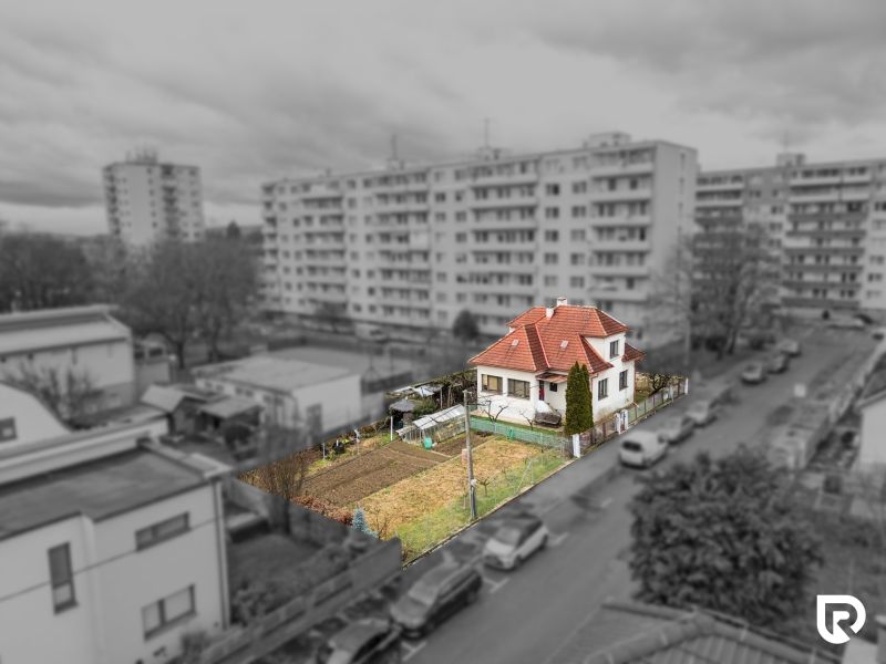 Rodinný dom s pozemkom 727m2, Tatranská ul. - Trenčín - Rodinný dom na Tatranskej ulici v Trenčíne obklopený záhradou, s výškovými budovami v pozadí.