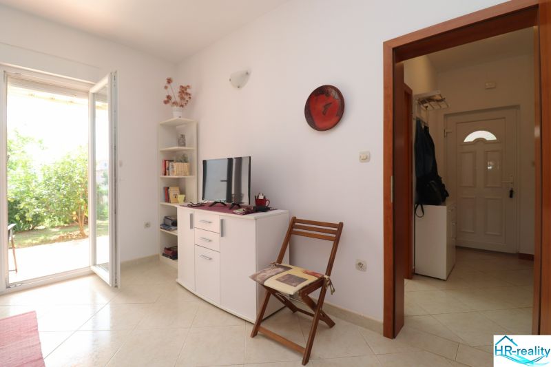 Chorvátsko, Vodice - zariadený bungalov, výhľad na more - Interiér rodinného domu s bielym nábytkom, televízorom a otvorenými dverami na záhradu.