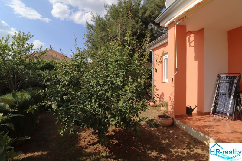 Chorvátsko, Vodice - zariadený bungalov, výhľad na more - Rodinný dom vo Vodiciach s oranžovou fasádou a upravenou záhradou.