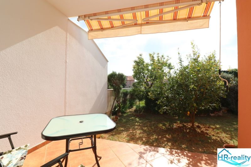 Chorvátsko, Vodice - zariadený bungalov, výhľad na more - Terasa rodinného domu vo Vodiciach so stolíkom, stoličkou a výhľadom na záhradu.
